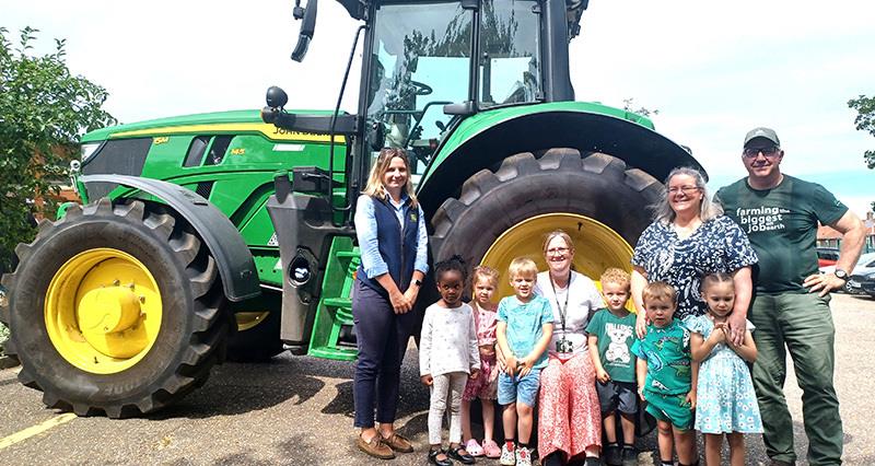 Alice Saunders and Tim Papworth stood in front of a tractor with pupils and teachers