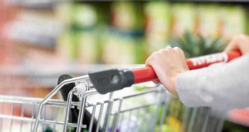 A close up picture of hands pushing a supermarket trolley